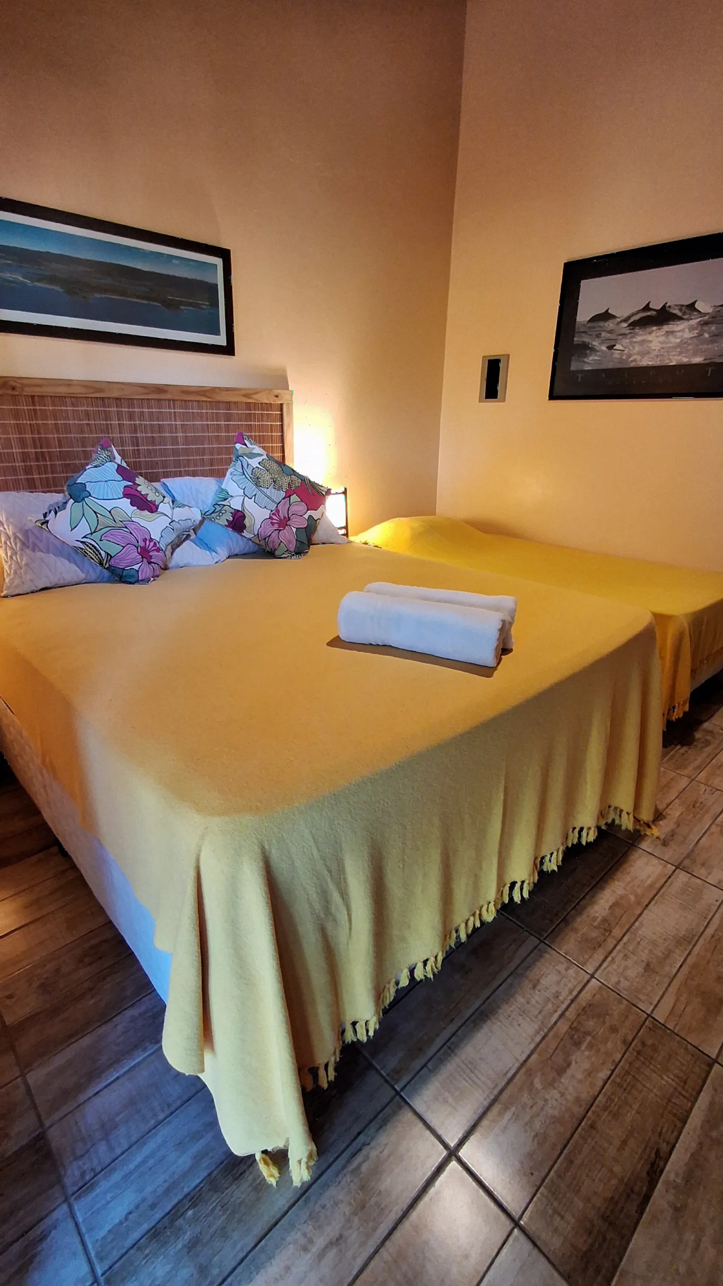 Cama de casal da Suíte 10 com almofadas estampadas e cabeceira de palha