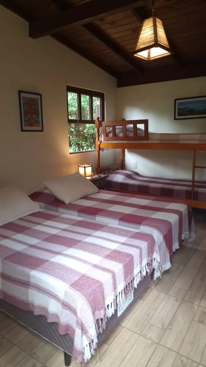 Quarto da Suíte 10 com cama de casal e beliche sob o teto de madeira