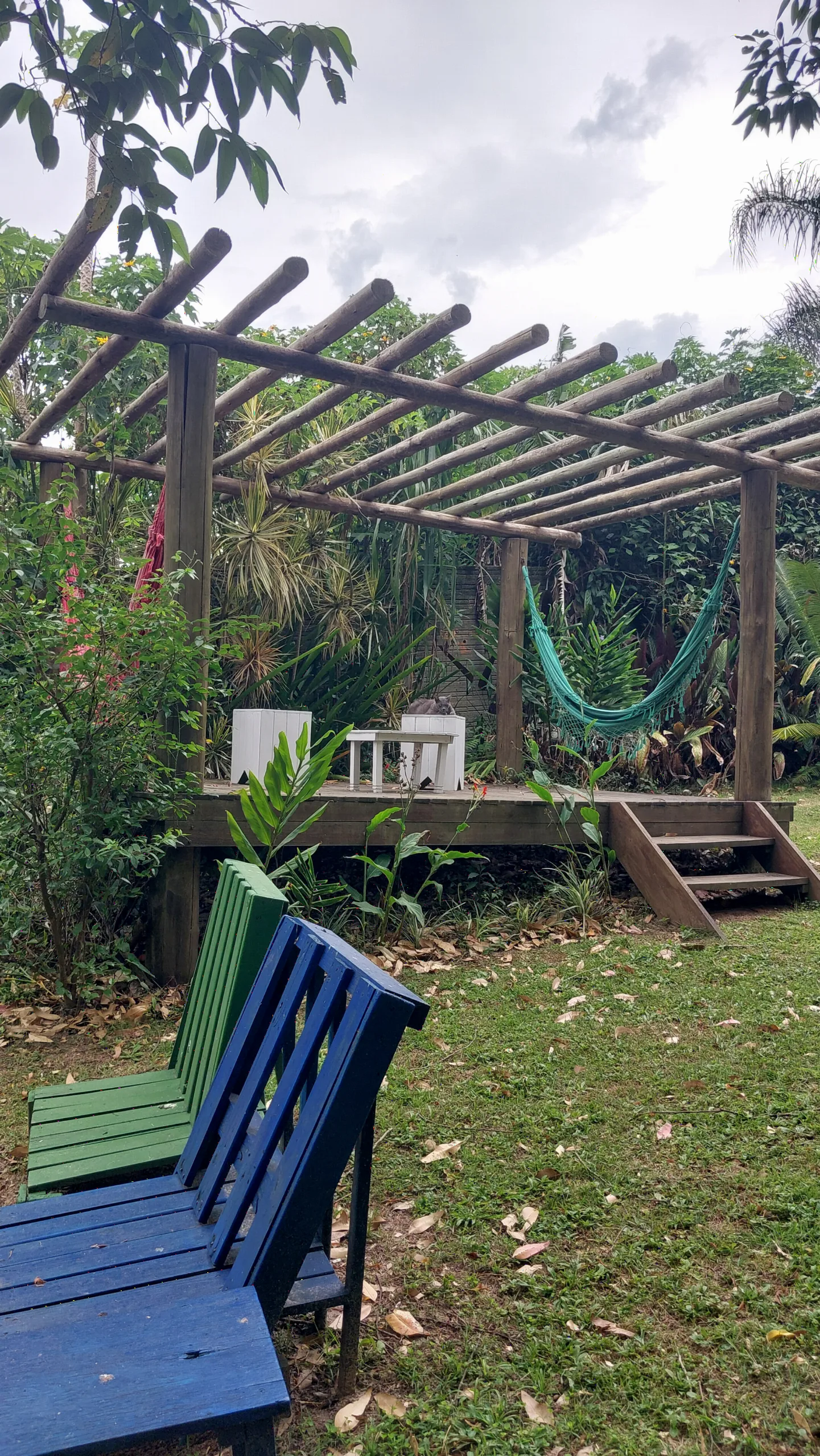 Pergolado de madeira do Espaço Zen com deck, redes e bancos coloridos no gramado